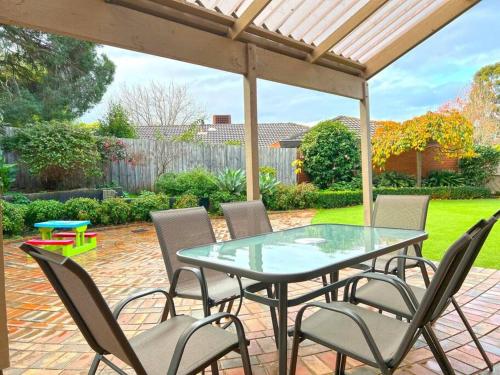 a glass table and chairs on a patio at Stylish Retreat Family House 5BRM Wheelers Hill in Wheelers Hill