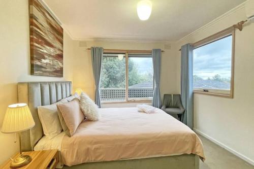 a bedroom with a large bed and a window at Stylish Retreat Family House 5BRM Wheelers Hill in Wheelers Hill