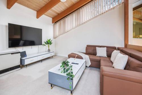a living room with a couch and a flat screen tv at Stylish Retreat Family House 5BRM Wheelers Hill in Wheelers Hill