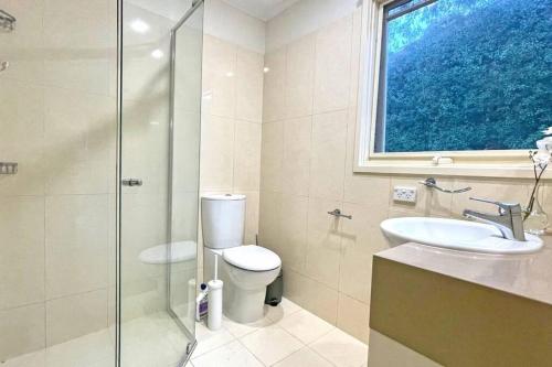 a bathroom with a toilet and a sink and a window at Stylish Retreat Family House 5BRM Wheelers Hill in Wheelers Hill
