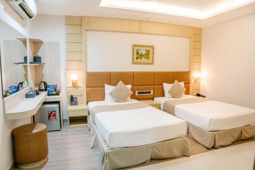 a hotel room with two beds and a desk at Holiday One Can Tho Hotel in Can Tho
