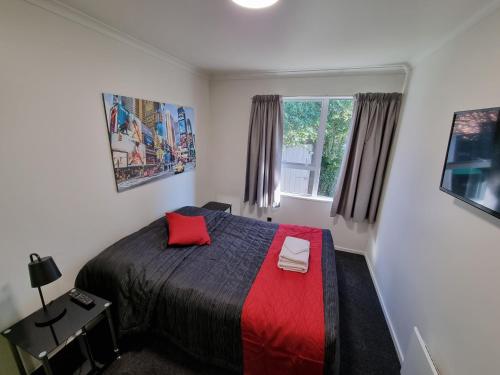 um quarto com uma cama com um cobertor vermelho e uma janela em Stay Timaru em Timaru