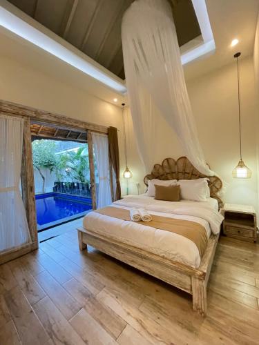 a bedroom with a large bed and a large window at Villa deluna in Jimbaran