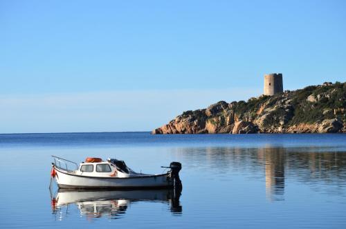 a small boat in the water with a lighthouse in the background at Hotel Jasmine in Teulada