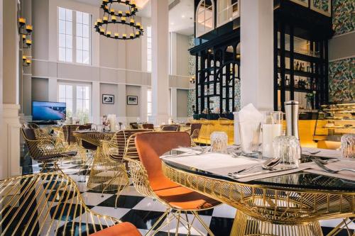 un restaurante con mesas y sillas de oro y una lámpara de araña en แกรนด์ ฟลอริด้า บีชฟร้อนท์ คอนโด รีสอร์ท พัทยา, en Na Jomtien