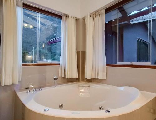 uma grande banheira branca numa casa de banho com janelas em Villas de Yanahuara em Ollantaytambo