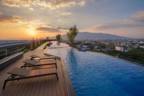 a swimming pool on top of a building with a sunset at The Astra Sky River Chiangmai_Sky pool_Old City in Chiang Mai