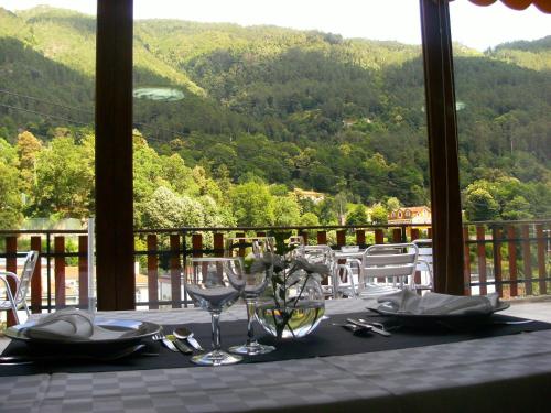a table with wine glasses and a view of the mountains at Moderna do Geres Hotel in Geres
