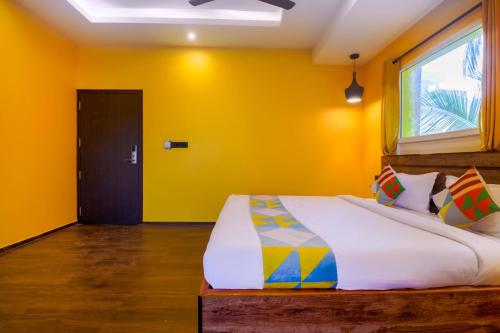 a bedroom with a bed with yellow walls and a window at Home Le Bliss Hotels Near Rock Beach in Puducherry