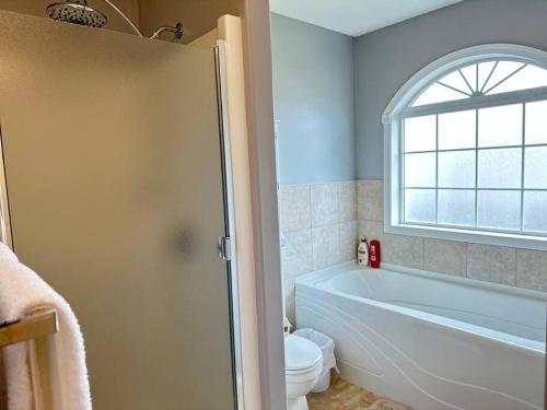 a bathroom with a tub and a toilet and a window at Comfortable 6 bedrooms house in Hinton