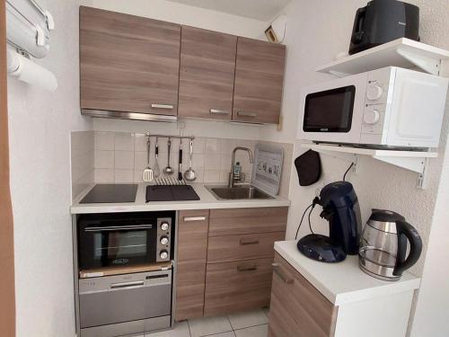 une petite cuisine avec une cuisinière et un micro-ondes dans l'établissement Appartement 2 pièces avec jardinet, proche plage et forêt à Saint-Georges-de-Didonne - FR-1-550-64, à Saint-Georges-de-Didonne