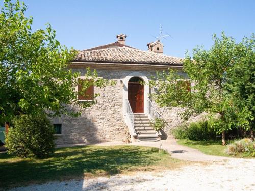 an old stone building with a red door and stairs at Welcoming holiday home in Urbania with pool in Urbania