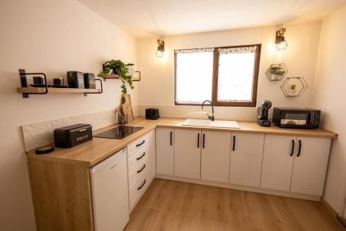 a kitchen with white cabinets and a sink and a window at MILLAR's in Sovata