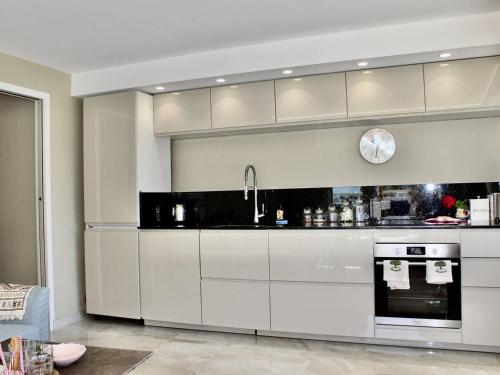 une cuisine avec des placards blancs et une horloge murale dans l'établissement Superbe appartement climatisé avec terrasse et jardin à Villeneuve Loubet Plage - FR-1-252A-106, à Villeneuve-Loubet