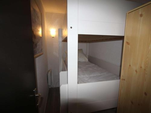 - un petit lit superposé blanc dans une petite chambre dans l'établissement Studio cabine fermée 4 pers au pied des pistes avec parking - Auris en Oisans - FR-1-297-334, à Auris