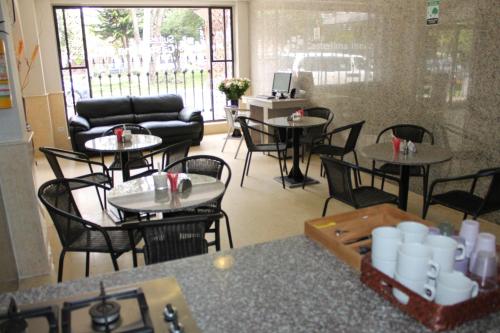 a restaurant with tables and chairs and a couch at Hotel Castellana Inn in Bogotá