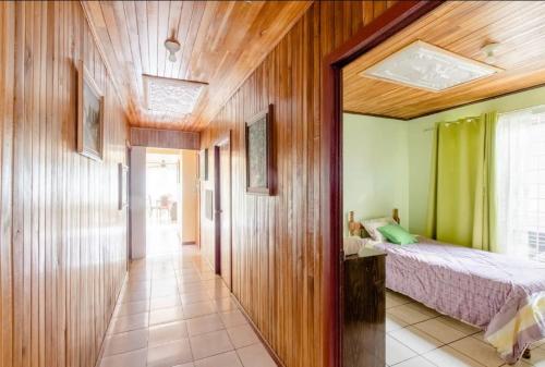 1 dormitorio con 1 cama y pared de madera en Casa Sarita - Cerca del Juan Castro, hospital y tribunales, en Quesada