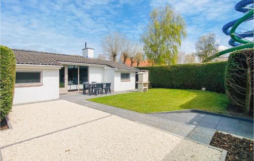 a house with a garden with a table and chairs at 3 Bedroom Awesome Home In Oostduinkerke in Oostduinkerke