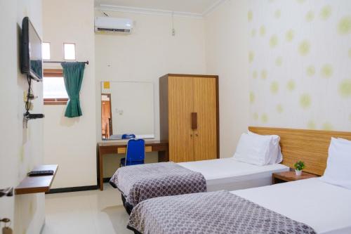 a room with two beds and a desk and a mirror at Homestay Griya Kinasih Syariah Pati Mitra RedDoorz in Pati