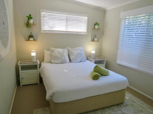 Schlafzimmer mit einem großen weißen Bett und einem Fenster in der Unterkunft Beach Cottage on Cassia Avenue, Central Coolum Beach in Coolum Beach