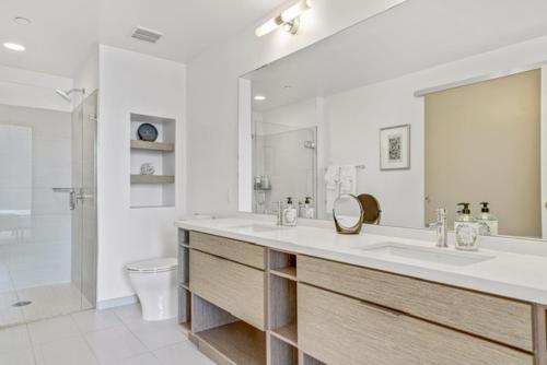a bathroom with a sink and a toilet and a mirror at Modern Luxury 2 Bed with Panoramic City Views in Downtown LA in Los Angeles