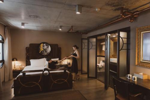 a woman standing next to a bed in a room at Art Mai Gallery Nimman Hotel Chiang Mai in Chiang Mai