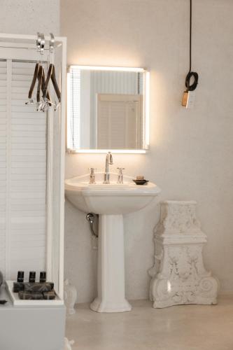 a white bathroom with a sink and a mirror at Art Mai Gallery Nimman Hotel Chiang Mai in Chiang Mai