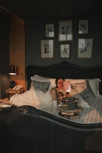 a woman laying in bed reading a book at Art Mai Gallery Nimman Hotel Chiang Mai in Chiang Mai