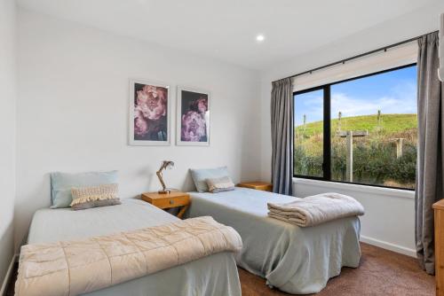 two beds in a room with a window at Sandhill Beach House - Te Horo Holiday Home in Te Horo