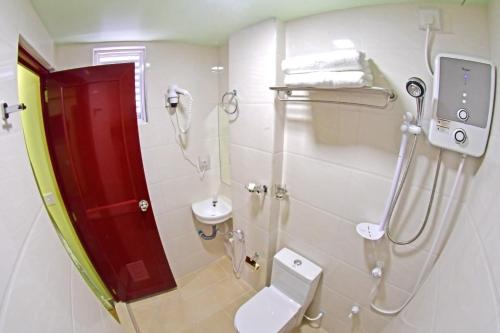 uma casa de banho com um chuveiro, um WC e um lavatório. em Tourist Inn em Malé