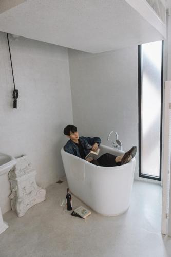 a man sitting in a bath tub in a bathroom at Art Mai Gallery Nimman Hotel Chiang Mai in Chiang Mai