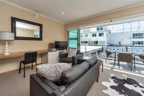 a living room with a couch and a table with chairs at QV Down at the Viaduct (861) in Auckland