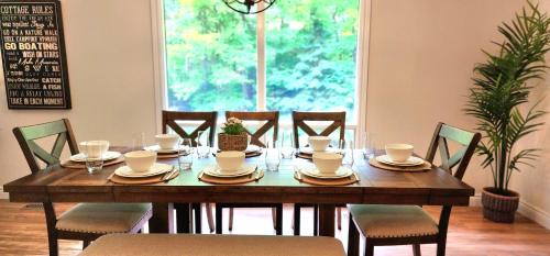 a dining room table with chairs and a wooden table and a table at Private 5 BR Muskoka Cottage Firepit+BBQ+Wi-Fi in Bracebridge
