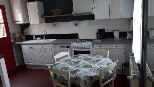 cocina con mesa y fogones horno superior en L'escale Arquaise, la maison au jardin fleuri à 5 min de dieppe en Arques-la-Bataille
