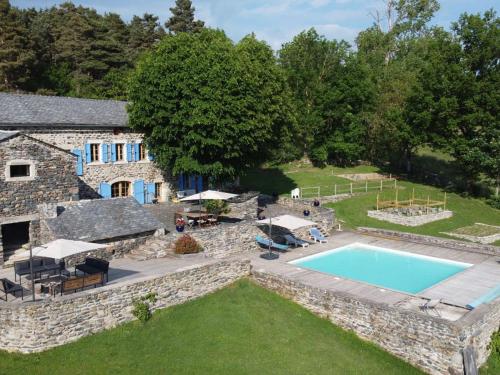 - une vue aérienne sur une maison en pierre avec une piscine dans l'établissement Séjour champêtre : magnifique ferme réhabilitée avec piscine, terrasses et confort moderne à St Étienne Lardeyrol - FR-1-582-389, à Saint-Étienne-Lardeyrol
