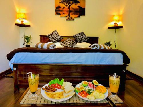 a bed with two plates of food on a table at The kingdom of ella in Ella