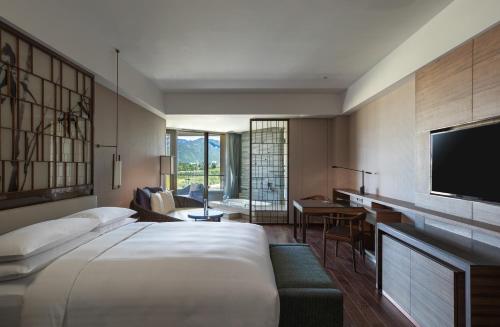 Cette chambre comprend un grand lit et une télévision. dans l'établissement Beijing Marriott Hotel Changping, à Changping