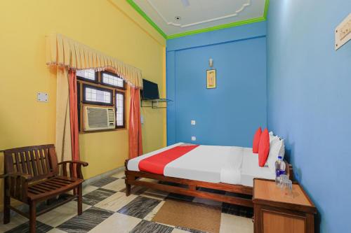 ein Schlafzimmer mit blauen und gelben Wänden sowie einem Bett und einem Stuhl in der Unterkunft OYO Flagship 86687 Hotel Anandlok in Haldwani-Kathgodam