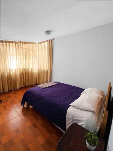 a bedroom with a purple bed and a table at Departamento con vista panoramica in Cusco