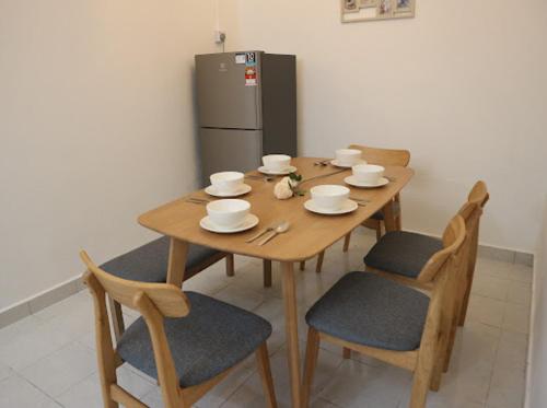 a wooden table with four chairs and a refrigerator at Hey homestay melaka in Melaka