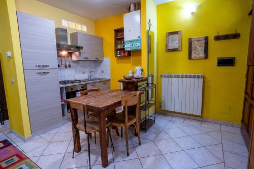 a kitchen with a wooden table and yellow walls at The Hamlet and the Valley, Il Paesino e la Vallata in Foiano della Chiana