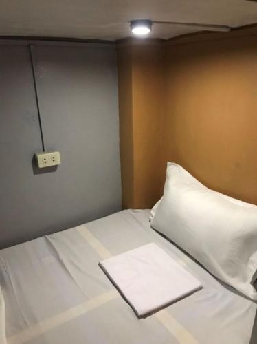 a bed with a white pillow and a lightswitch at Budget Transient Capsule Room Makati near Ayala and Buendia in Manila