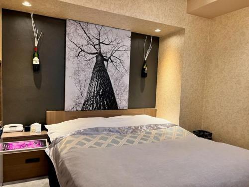 a bedroom with a bed and a picture of a tree at Hotel Opus -Adult only- in Kasugai