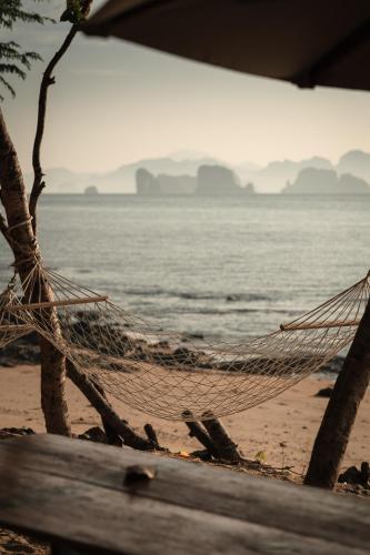 a hammock on a beach next to the water at Touch Glamping Koh Yao Noi ทัช แกรมปิ้ง เกาะยาวน้อย in Ko Yao Noi