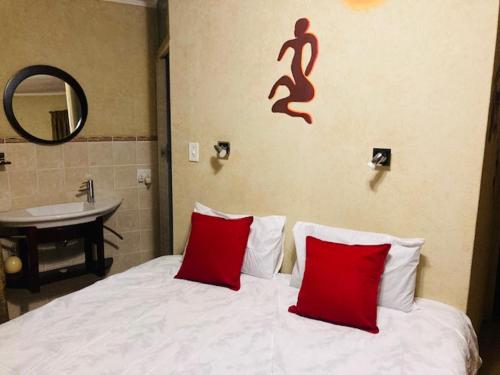 1 dormitorio con cama con almohadas rojas y lavamanos en Eagle Crest Executive Lodge, en Edenvale