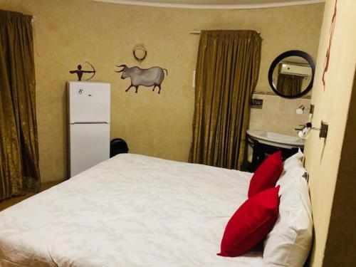 a bedroom with a bed with red pillows and a refrigerator at Eagle Crest Executive Lodge in Edenvale