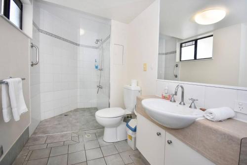 a white bathroom with a toilet and a sink at Mooloolaba Perfect - beach, wharf, dining ZE2 in Mooloolaba
