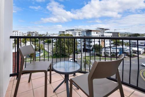 a balcony with chairs and a table and a view of a city at Mooloolaba Perfect - beach, wharf, dining ZE2 in Mooloolaba