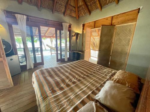 1 dormitorio con 1 cama en una habitación con puertas correderas en Los Bungalows de Blanca - Playa La Saladita, en La Majahua