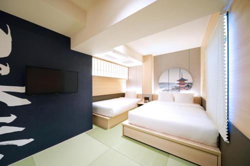 a bedroom with two beds and a flat screen tv at Travelodge Kyoto Shijo Kawaramachi in Kyoto
